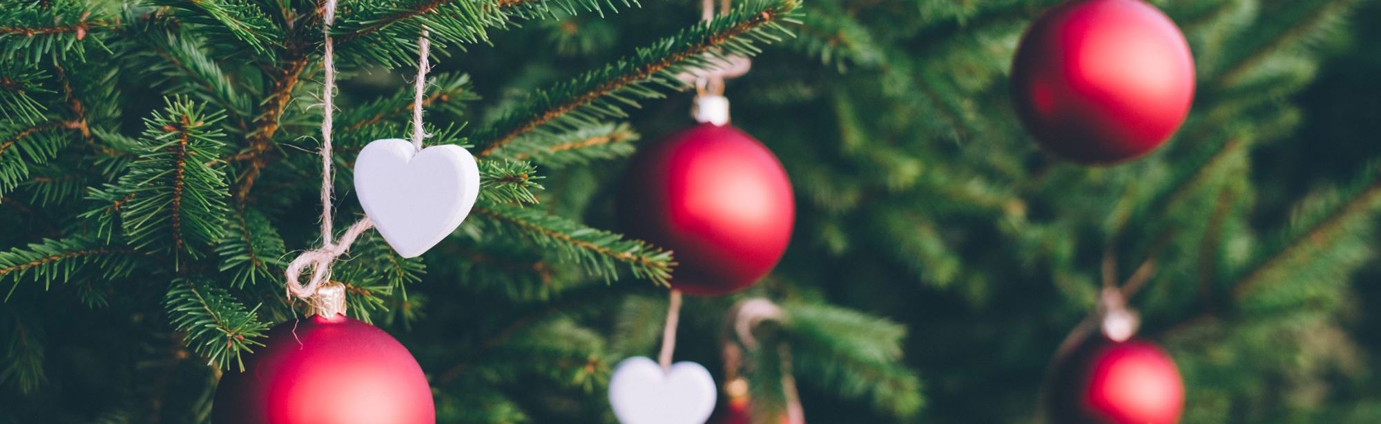 Close up van rode kerstballen en witte hartjes in dennenboom